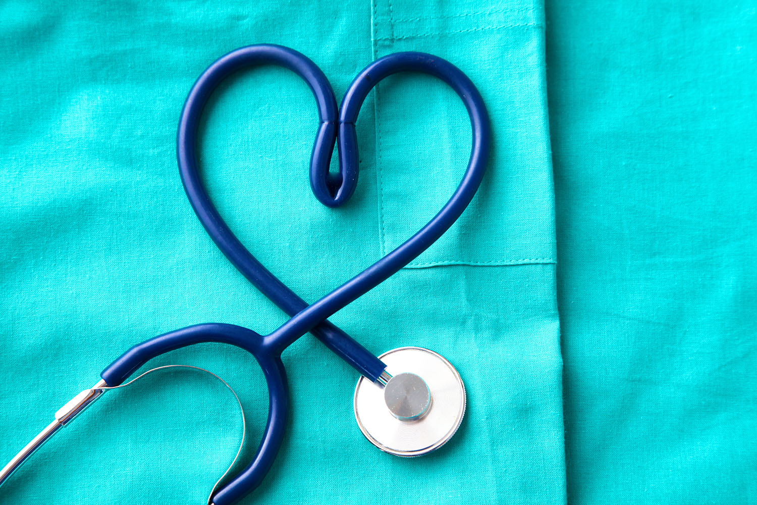 stethoscope shaping heart and clipboard on medical uniform, closeup