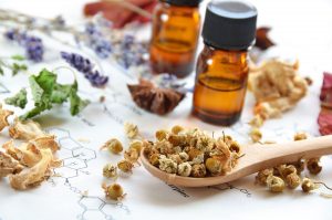 essential oils with dried herbs on science sheet